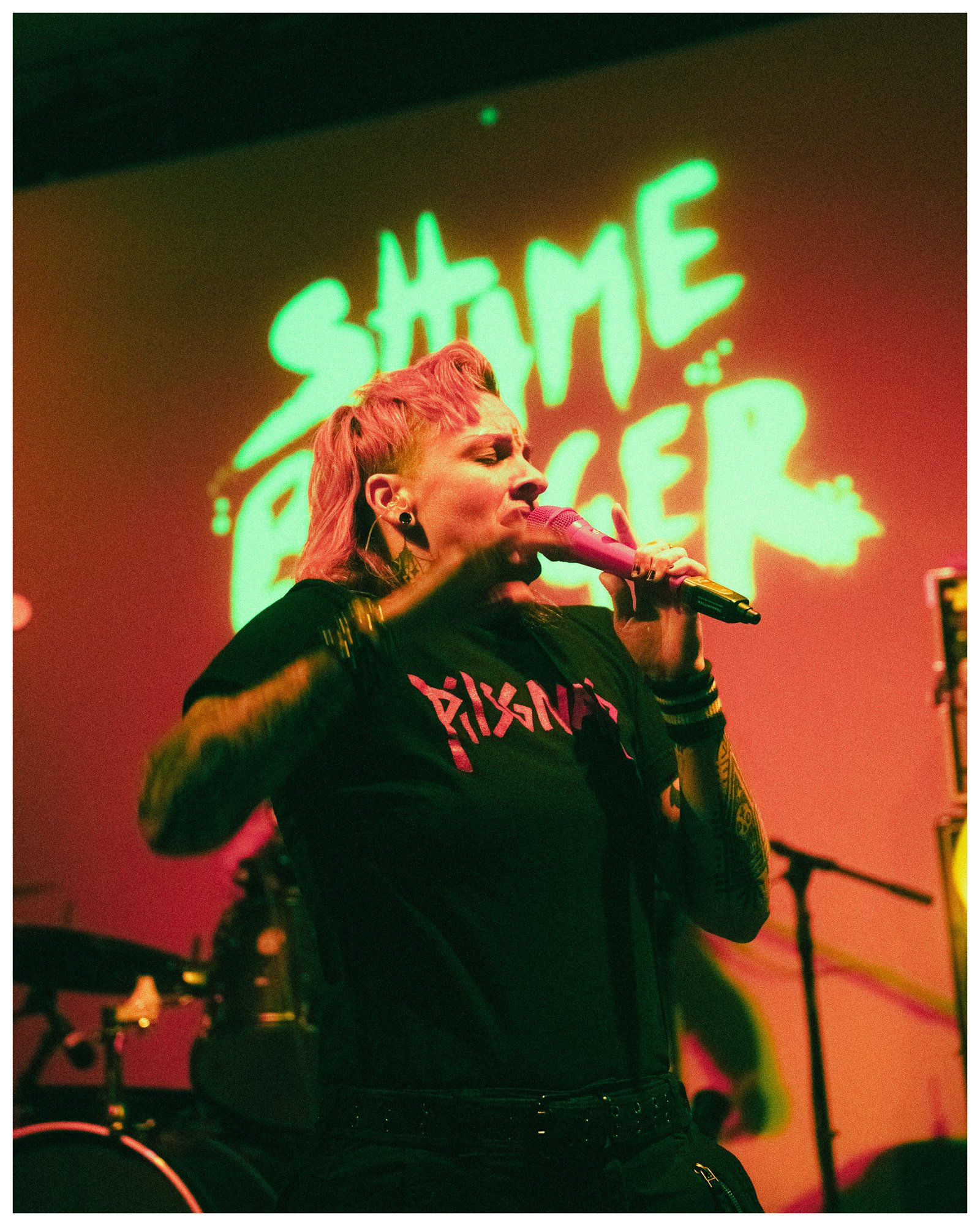 Rowan performing on stage with Shame Banger projected behind them.